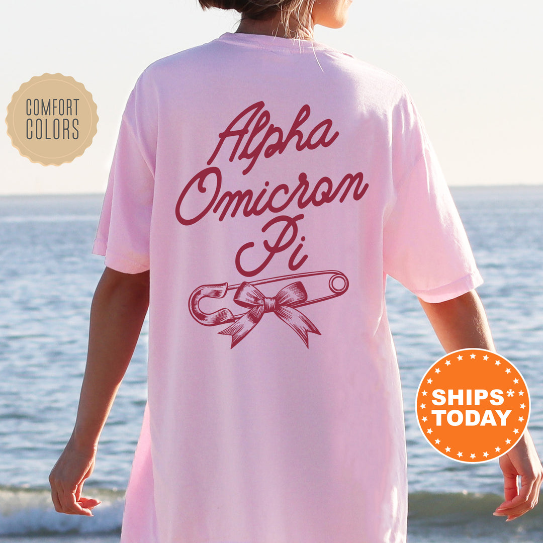 a woman wearing a pink shirt with the words apha omicron pi on