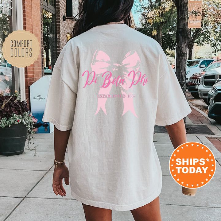 a woman walking down a sidewalk wearing a white shirt with a pink ribbon on it