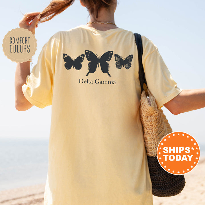 a woman walking on the beach with a butterfly shirt on