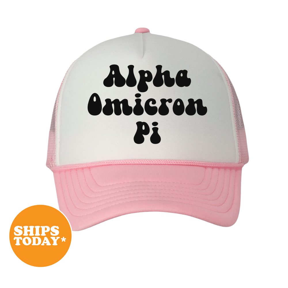 A pink and white baseball cap with the text "Alpha Omega Pi" printed on it.