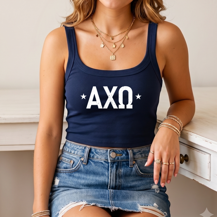 A woman wearing a navy blue crop top with the text "AXQ" and a denim skirt, sitting on a white desk.