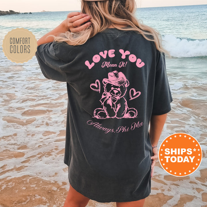a woman standing on the beach wearing a love you shirt