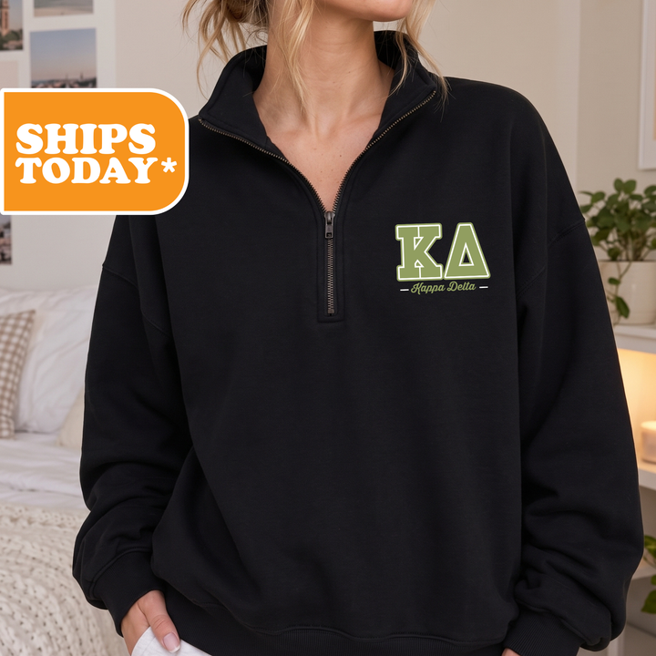 A person wearing a black sweatshirt with the letters 'KA' and 'Delta' printed on it.