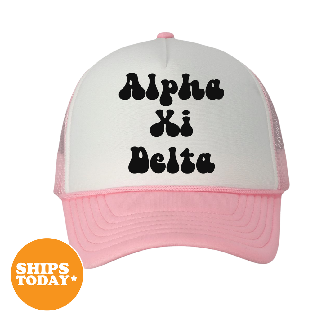A pink and white baseball cap with the text "Alpha Kappa Delta" printed on it.