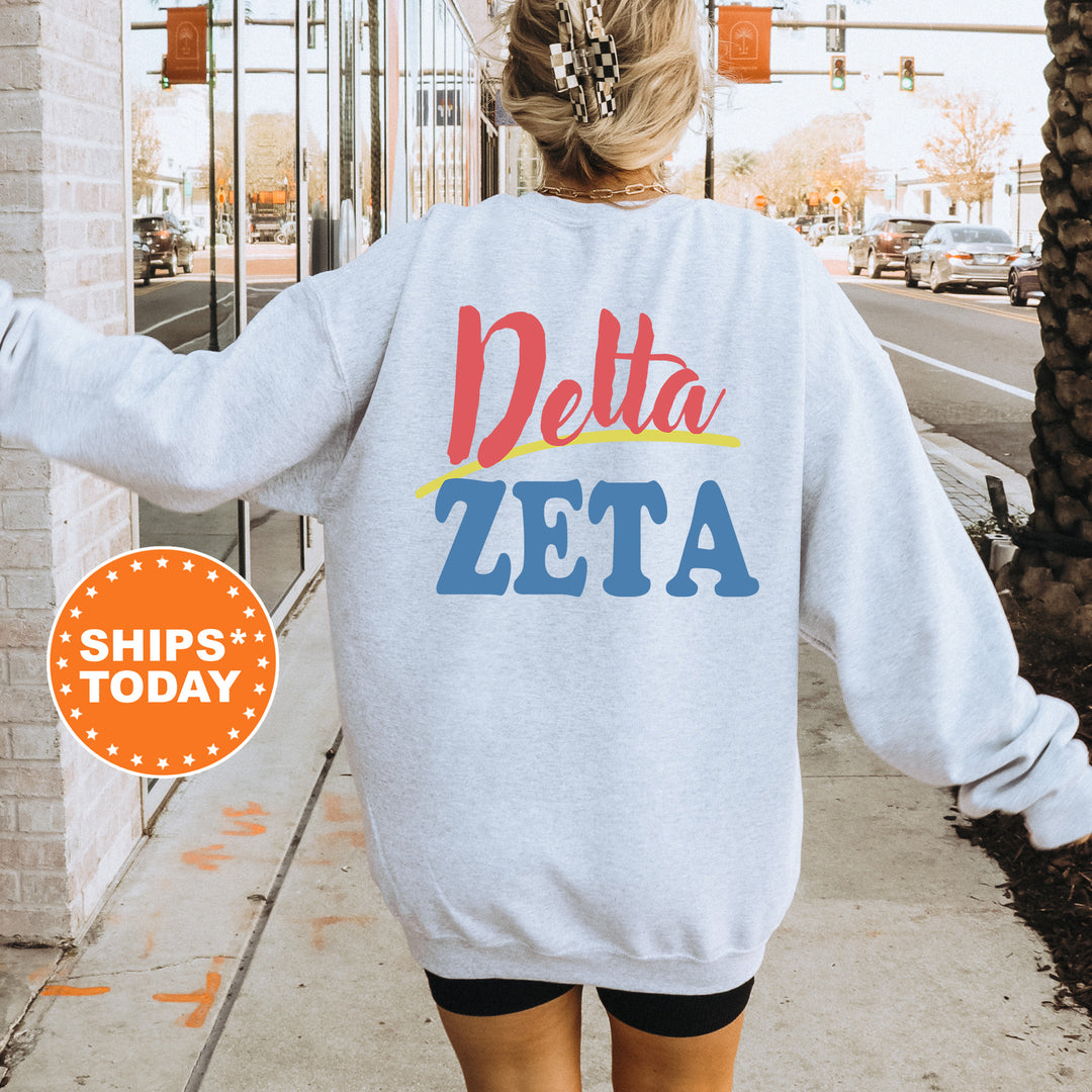 A person wearing a white sweatshirt with the text "Delta Zeta" printed on it, standing on a sidewalk with a city street in the background.