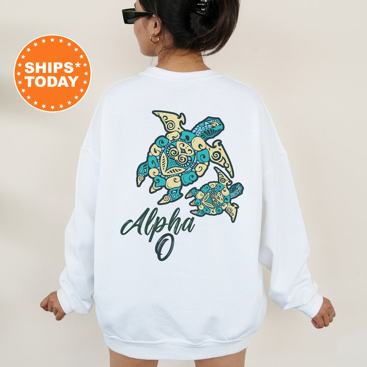 A person wearing a white sweatshirt with a colorful turtle design and the word "Alpha" printed on it.