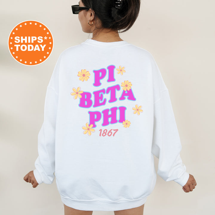 A person wearing a white sweatshirt with the text "PI BETA PHI 1867" printed on it, along with colorful floral designs.