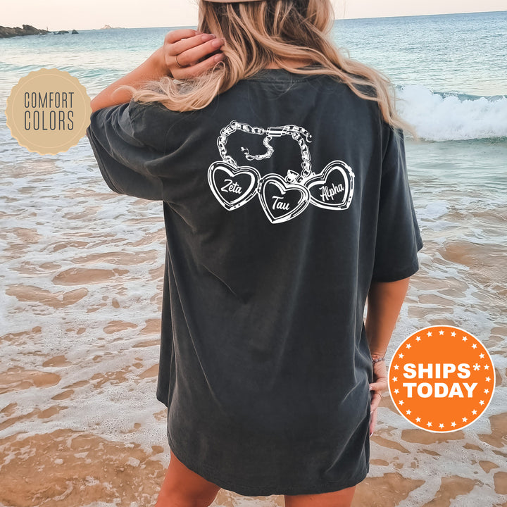 A woman standing on a beach with her back to the camera, wearing a black t-shirt with a graphic design on the back.