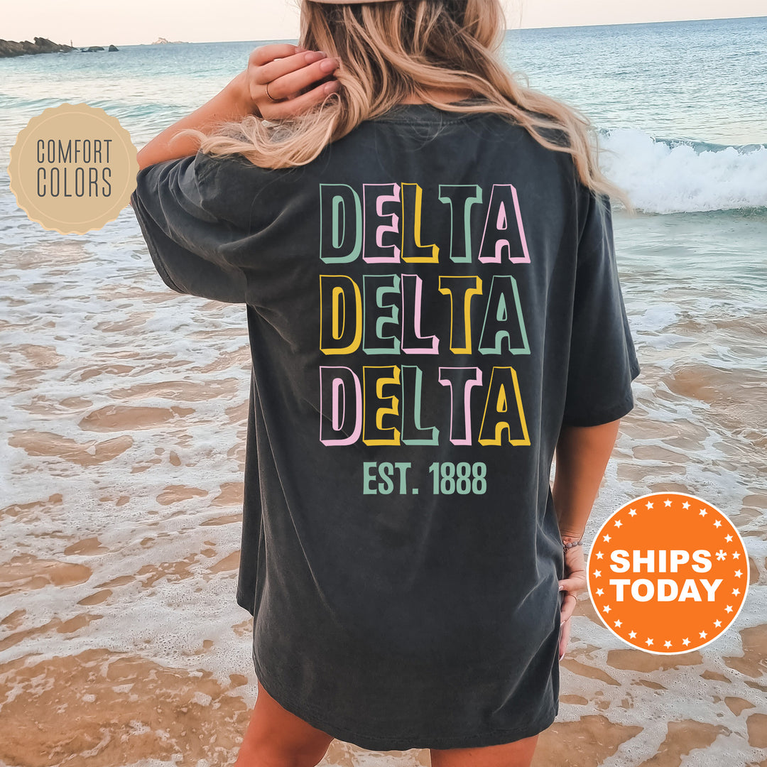 a woman standing on a beach wearing a black delta delta shirt