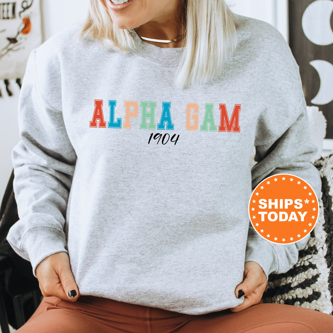 a woman sitting on a chair wearing a gray sweatshirt with the word alpba