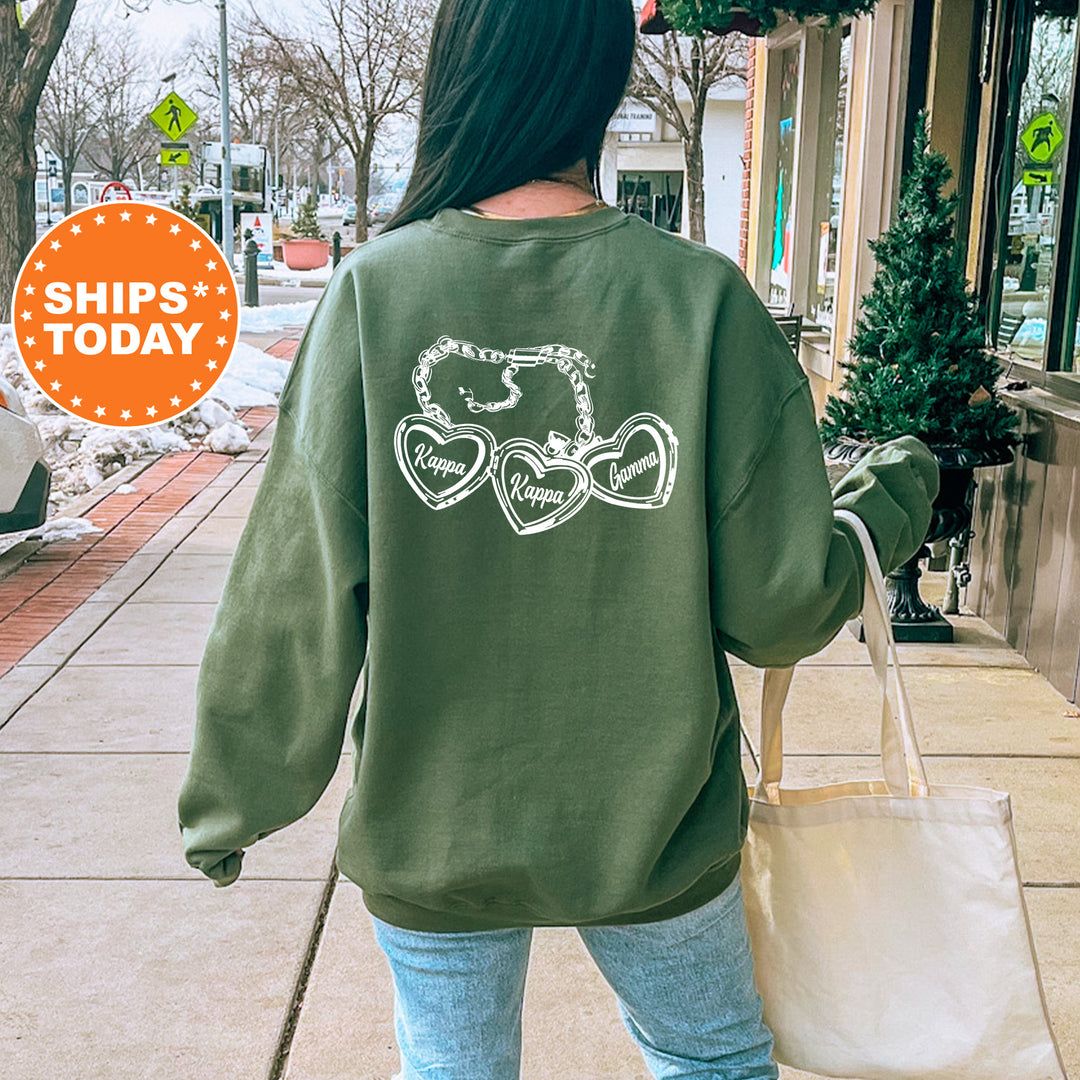A person wearing a green sweatshirt with a graphic design on the back is walking down a sidewalk, carrying a white bag.