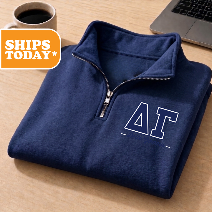 A navy blue sweatshirt with a white "ΑΛΑ" logo is folded and placed on a wooden surface, accompanied by a cup of coffee and a laptop.