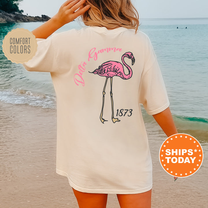 a woman standing on a beach wearing a pink flamingo t - shirt