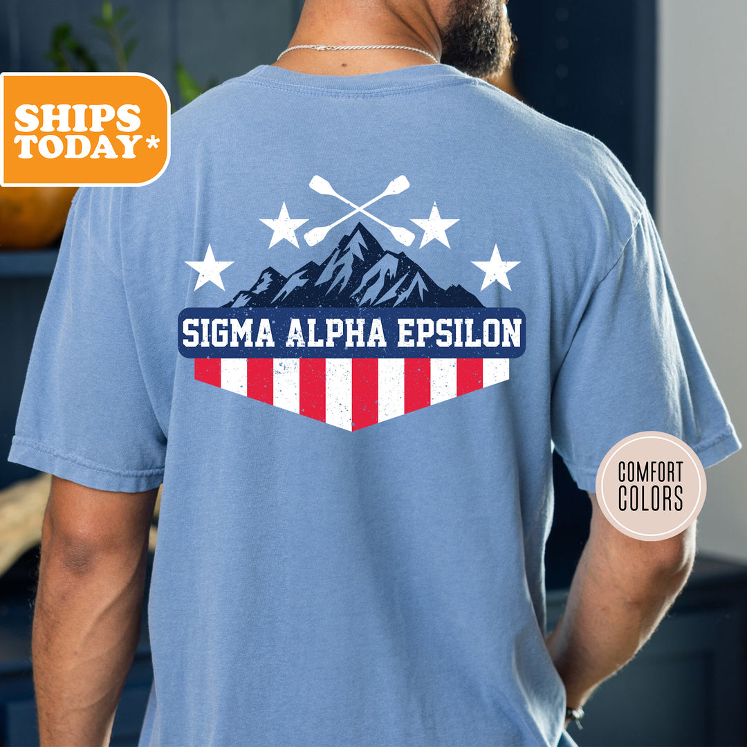 a man wearing a blue shirt with a flag and mountains on it