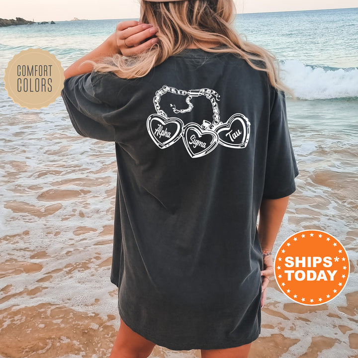 A woman wearing a black t-shirt with a graphic design on the back is standing on a beach, with the ocean visible in the background.