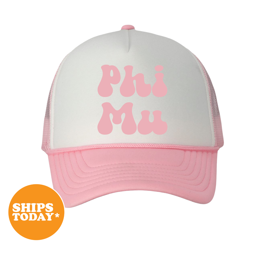 A white and pink baseball cap with the text "Phi Mu" printed on it.