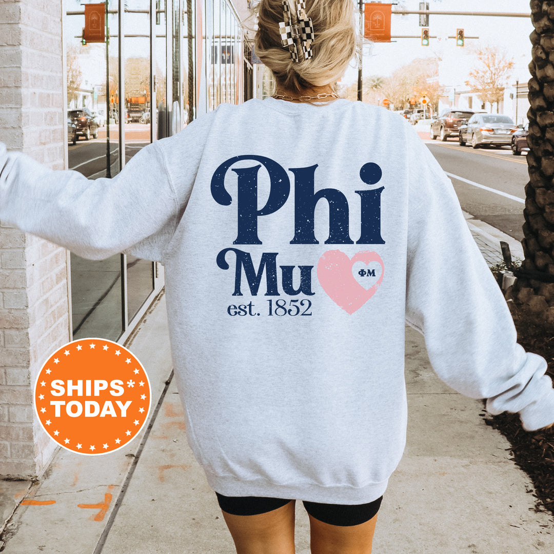 a woman walking down a sidewalk wearing a phi mu sweatshirt