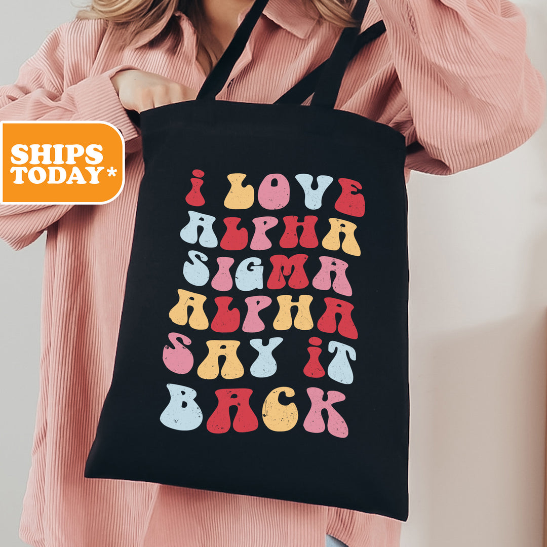 a woman holding a black tote bag with colorful letters