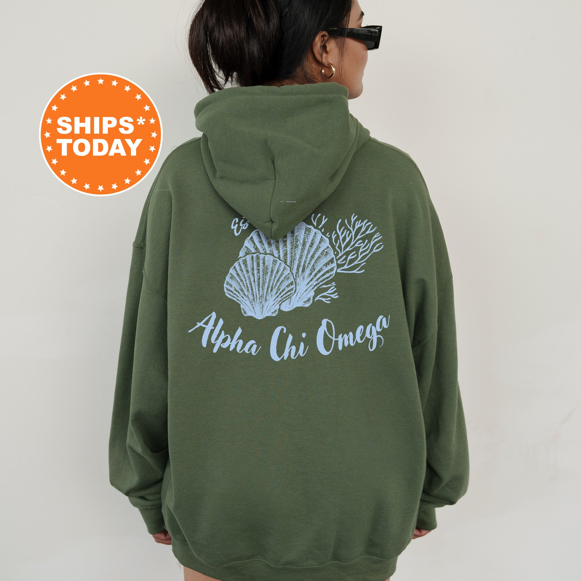 A person wearing a green hoodie with a graphic of seashells and the text 