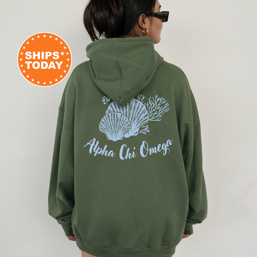 A person wearing a green hoodie with a graphic of seashells and the text "Alpha Chi Omega" printed on the back.