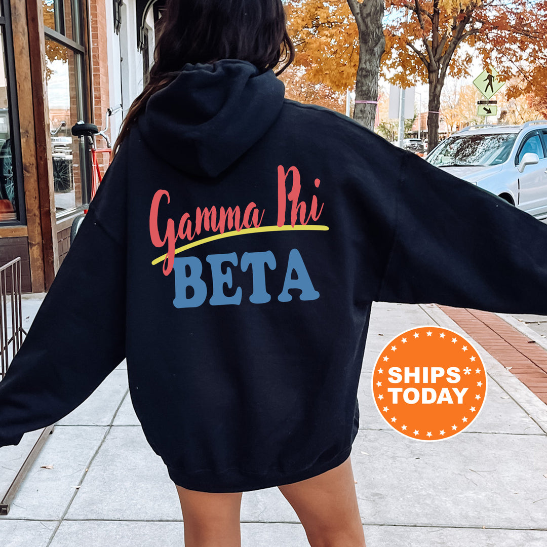 A person wearing a black hoodie with the text "Gamma Phi Beta" printed on it, standing on a sidewalk with a car and a building in the background.