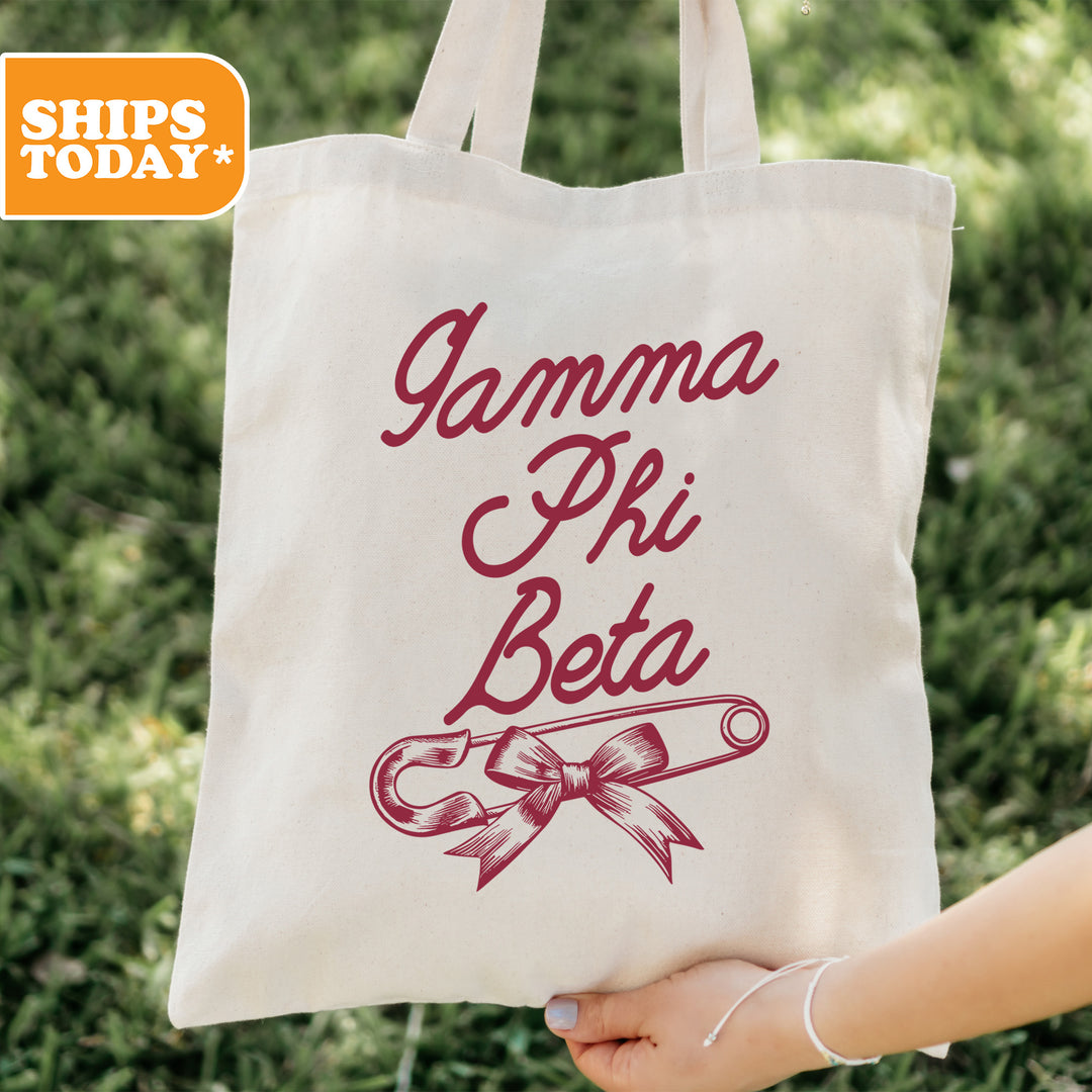a person holding a tote bag with the words gama phi beta on