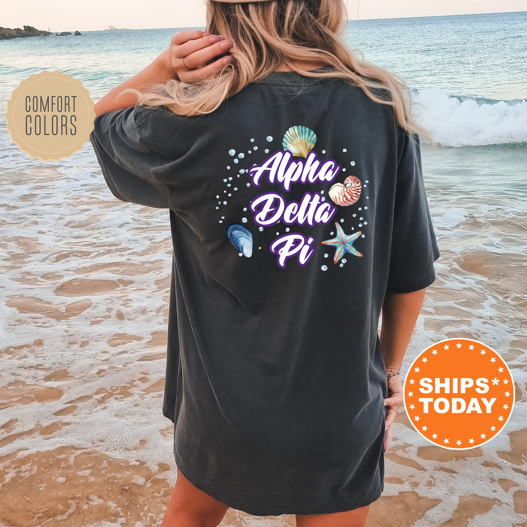 a woman standing on a beach wearing a black shirt