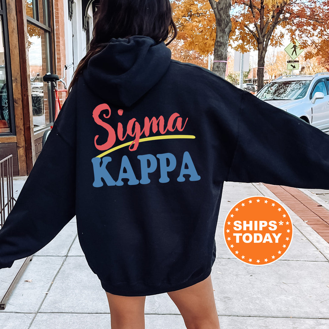 A person wearing a black hoodie with the Sigma Kappa logo printed on it, standing on a sidewalk with a car and a building in the background.