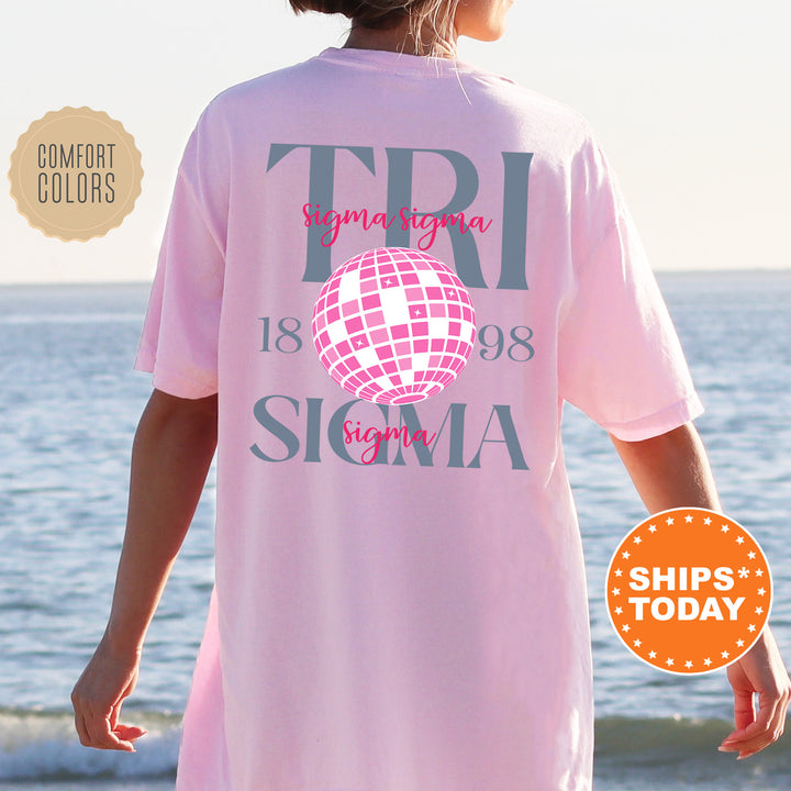 a woman standing on a beach wearing a pink shirt