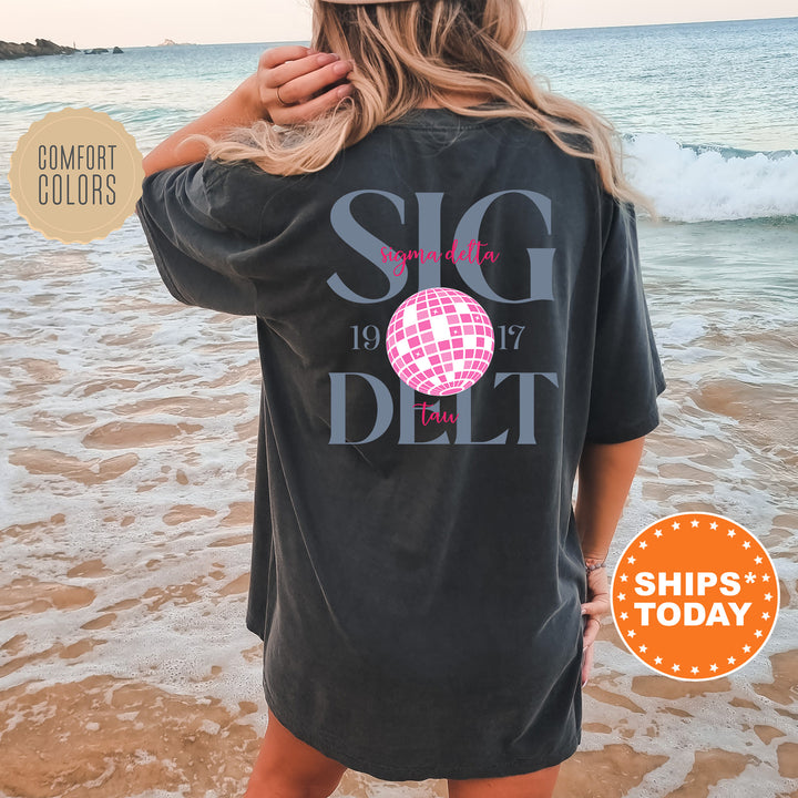 a woman standing on a beach wearing a t - shirt
