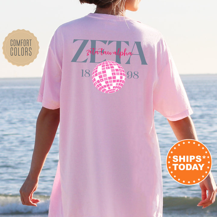 a woman standing on a beach wearing a pink shirt