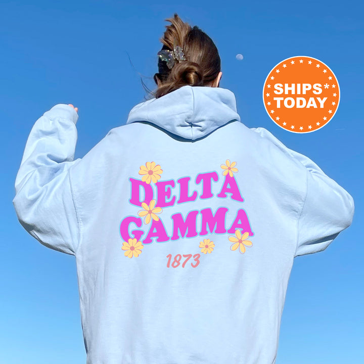A person wearing a light blue hoodie with the text "DELTA GAMMA 1873" printed on it, standing against a clear blue sky.