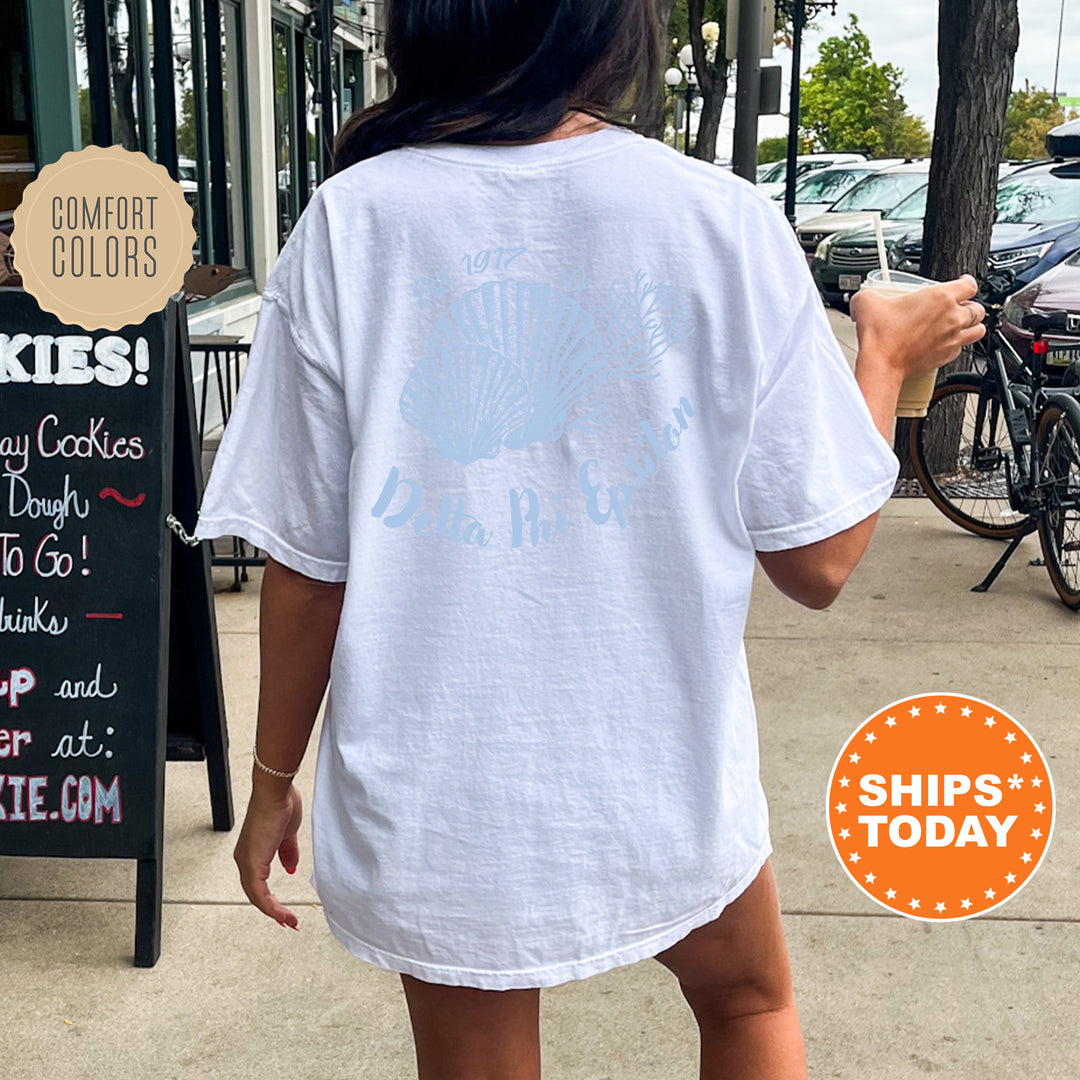 A person wearing a white t-shirt with a graphic design is walking on a sidewalk, with a chalkboard sign and bicycles visible in the background.
