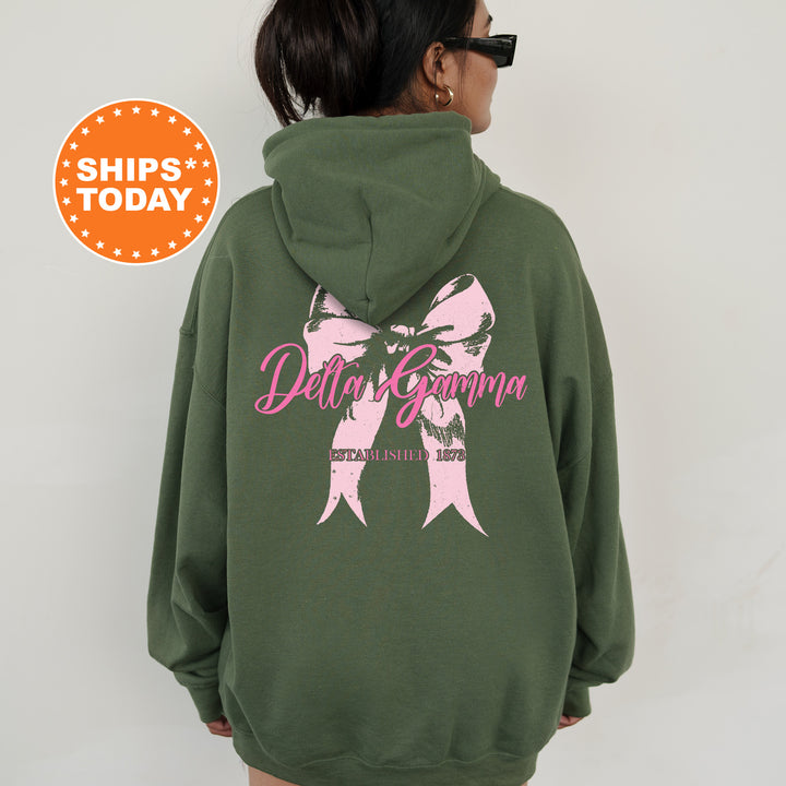 a woman wearing a green sweatshirt with a pink bow on it