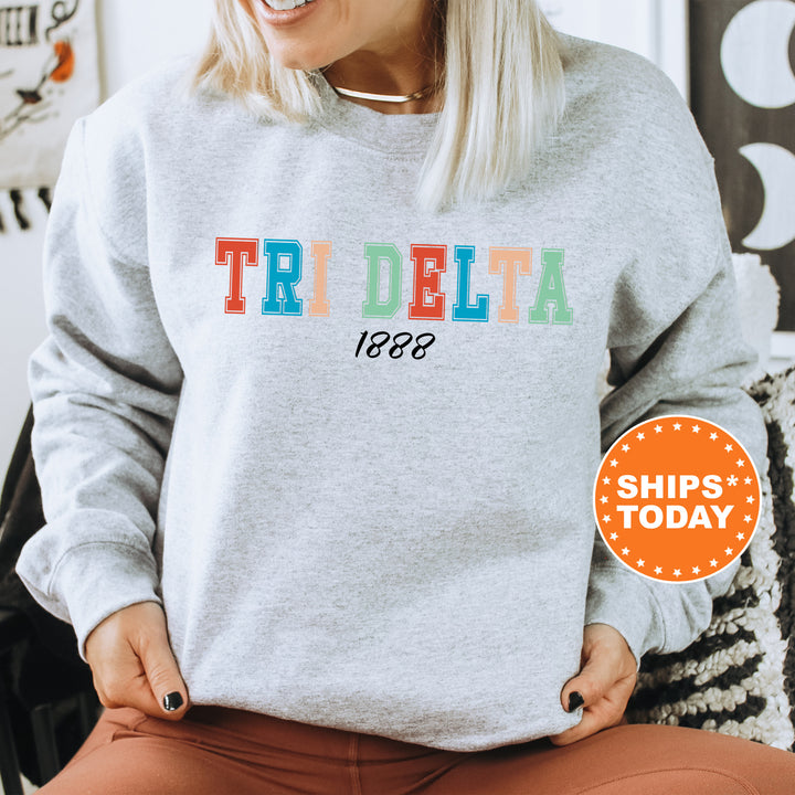 a woman sitting on a chair wearing a sweatshirt with the word tri delta on it
