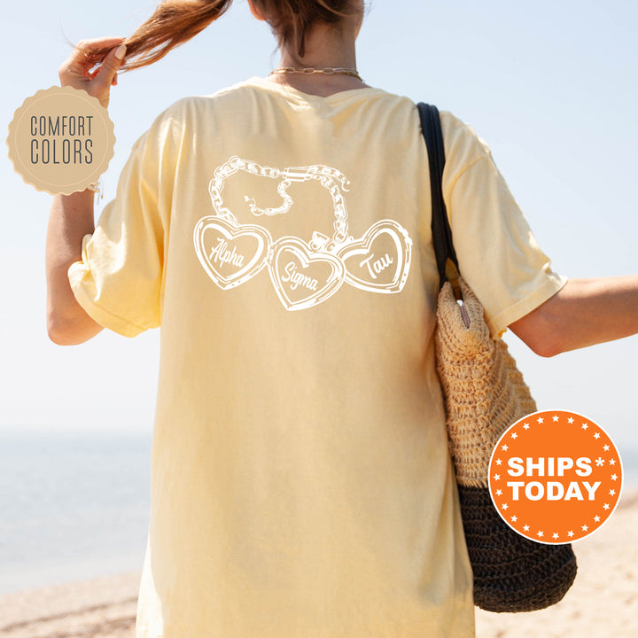 A person wearing a yellow t-shirt with a graphic design on the back, standing on a beach with a handbag.