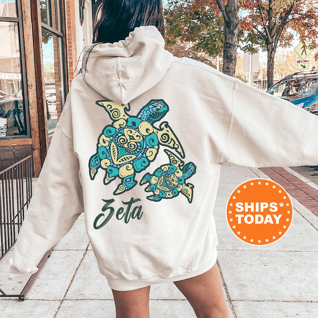 A person wearing a white hoodie with a colorful turtle design on the back, standing on a sidewalk.