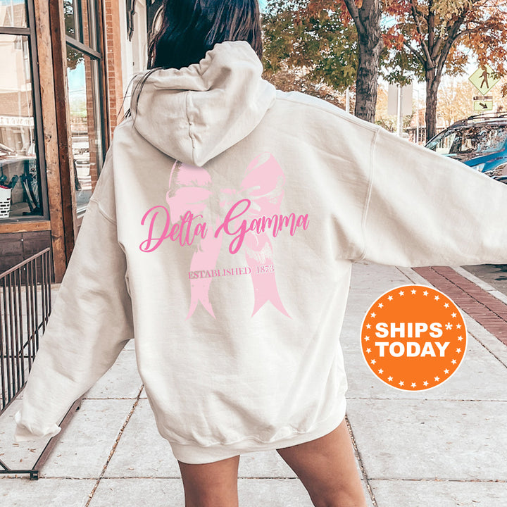 a woman walking down a sidewalk with a pink ribbon on her hoodie