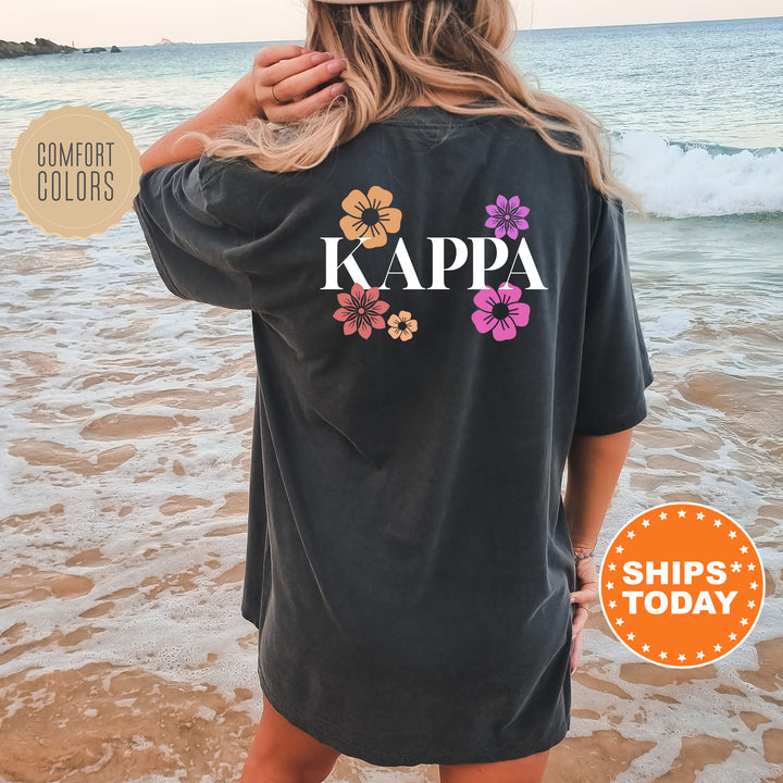 a woman standing on a beach wearing a black kapa shirt