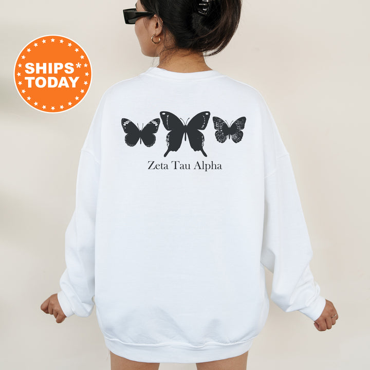 a woman wearing a white sweatshirt with black butterflies on it