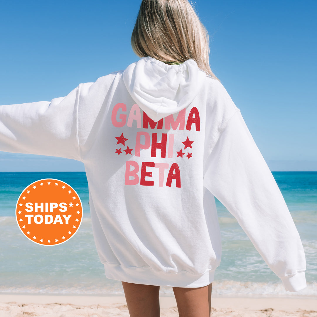 a woman standing on a beach wearing a white hoodie