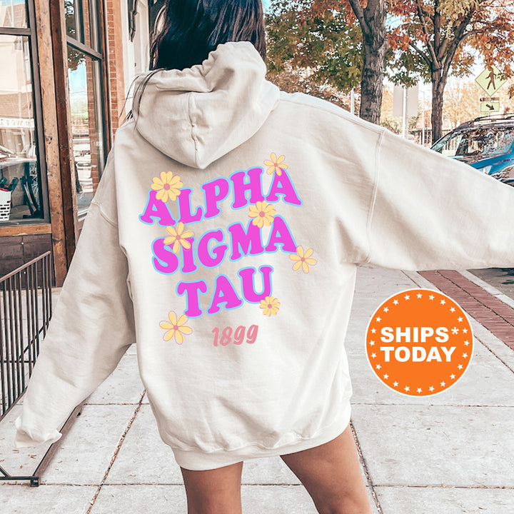 A person wearing a white hoodie with the text "ALPHA SIGMA TAU" printed on it, standing on a sidewalk.