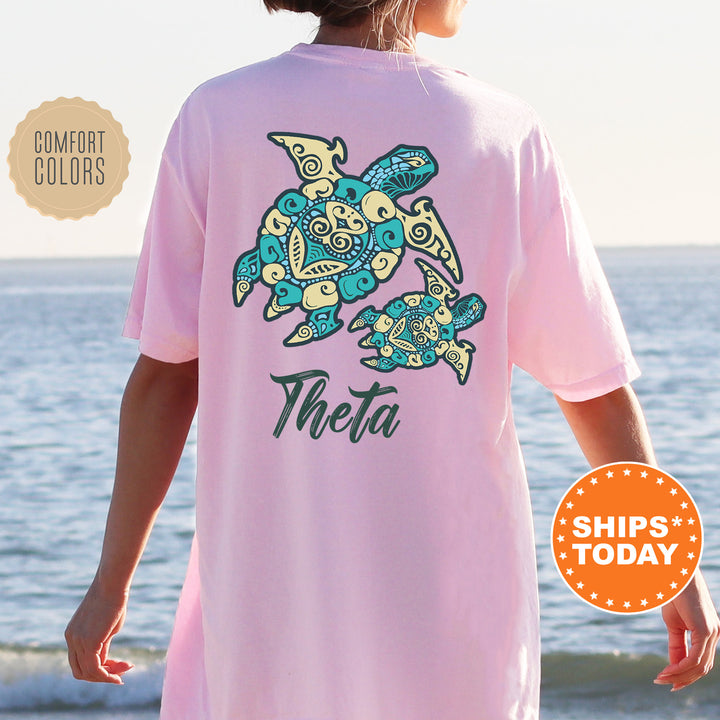 A person wearing a pink t-shirt with a design of two stylized turtles, one larger and one smaller, on the back.
