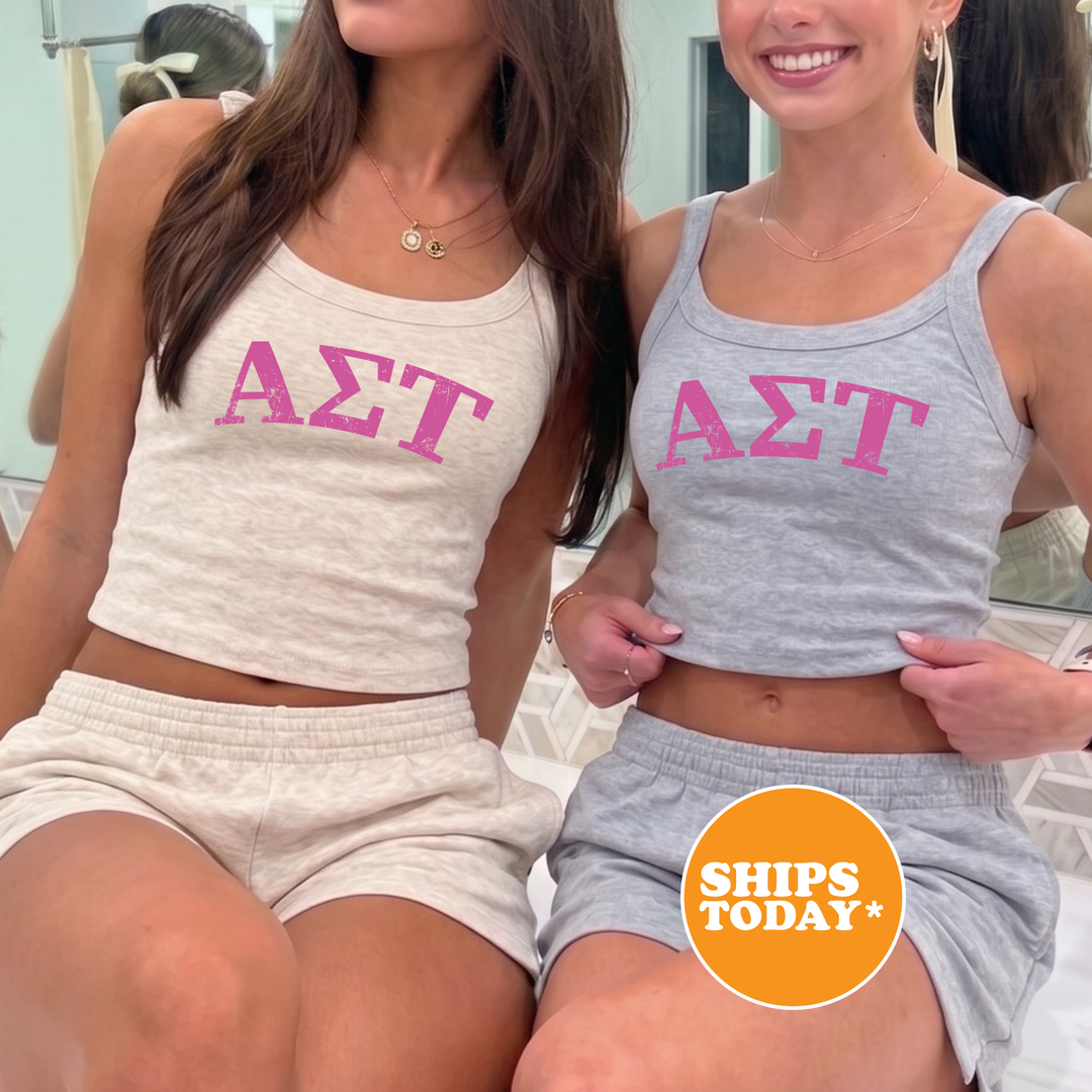 Two women wearing matching tank tops with the letters 'ΑΛΑ' printed on them, posing together in front of a mirror.