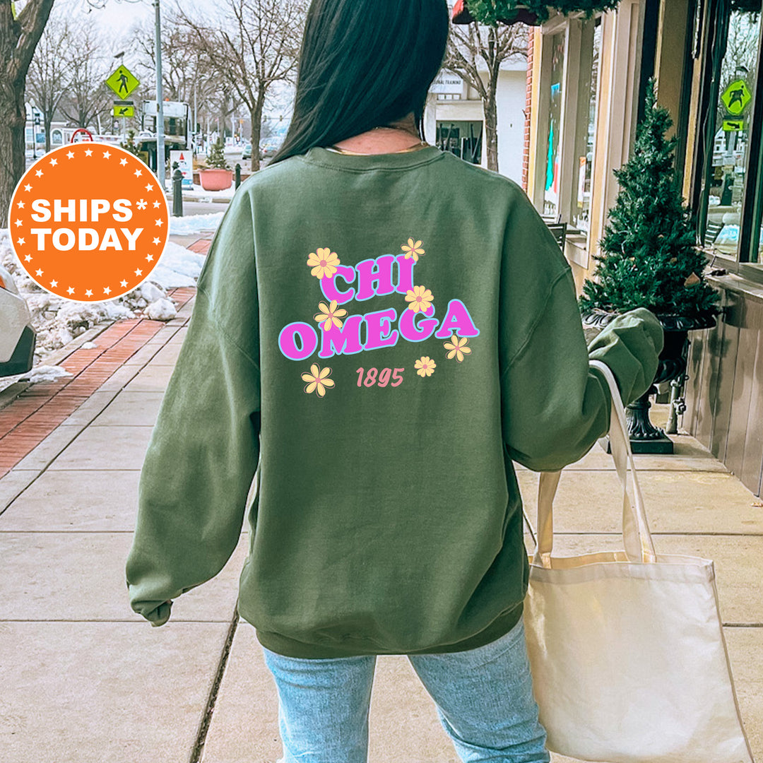 A person wearing a green sweatshirt with the text "CHI OMEGA" and "1995" printed on it, walking down a city street.