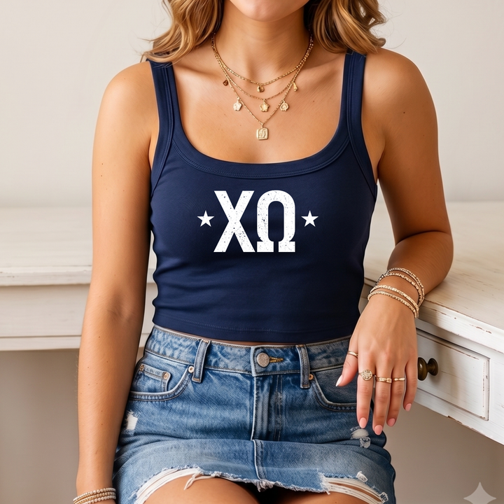 A woman wearing a navy blue crop top with white text and a denim skirt, sitting on a white surface.