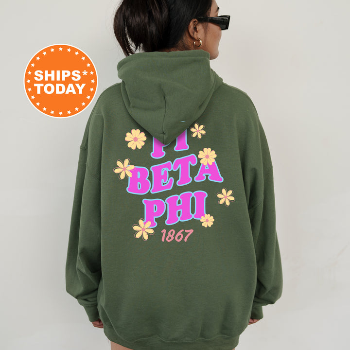 A person wearing a green hoodie with the text "Beta Phi" and "1867" printed on it, along with colorful flower designs.