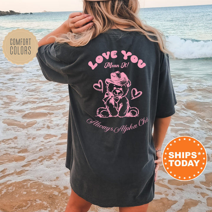 a woman standing on the beach wearing a love you shirt