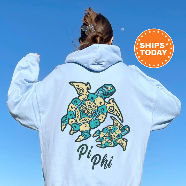 A person wearing a light blue hoodie with a colorful turtle design and the text "Pi Phi" printed on the back.