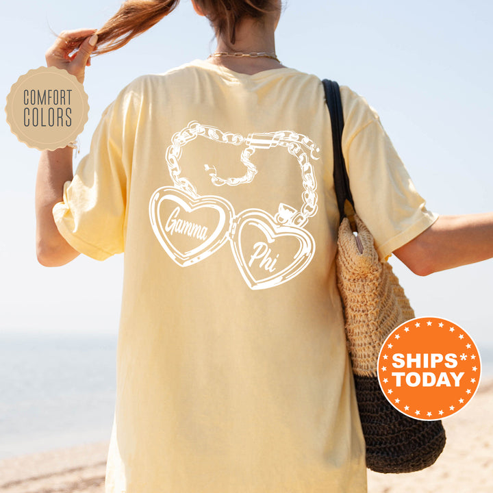A person wearing a yellow t-shirt with a graphic design on the back, standing on a beach with a handbag and a sign that says "SHIPS TODAY".